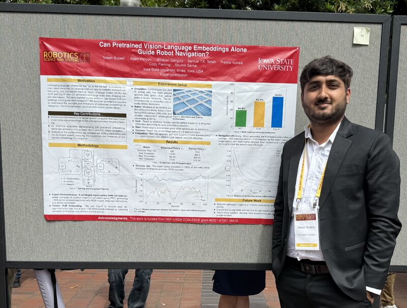 A student in a dark suit standing beside a poster with a red Iowa State University header.