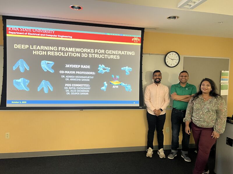 Three people standing in front of a projected slide titled "Deep Learning Frameworks for Generating High Resolution 3D Structures".