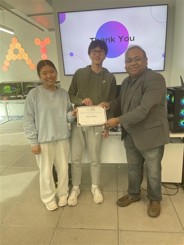 Two students and a man holding a TrAC certificate in front of a screen reading "Thank You".