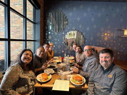 Eight people smiling around a restaurant table with plates of food.